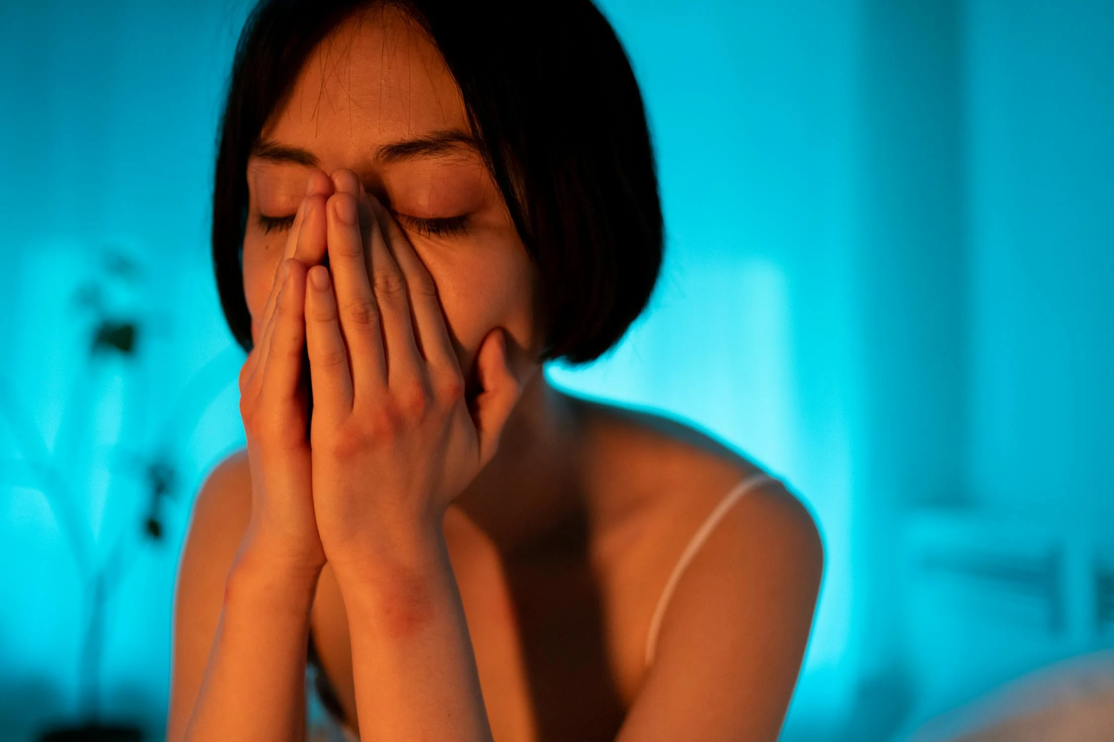 Une femme triste dans une pièce à la lumière bleue | Source : Pexels