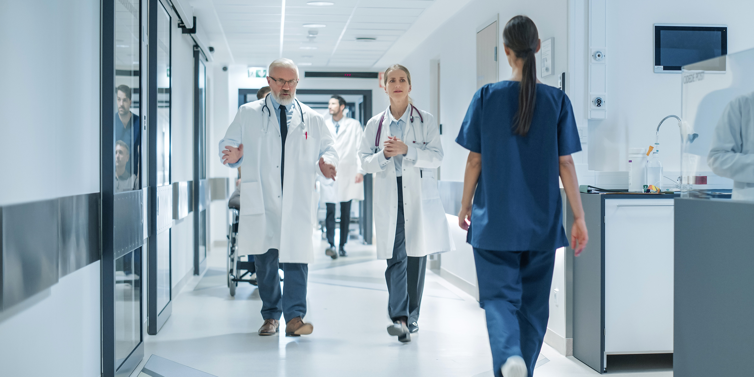 Des médecins et du personnel médical marchent dans un couloir d'hôpital très éclairé pendant une garde occupée | Source : Shutterstock