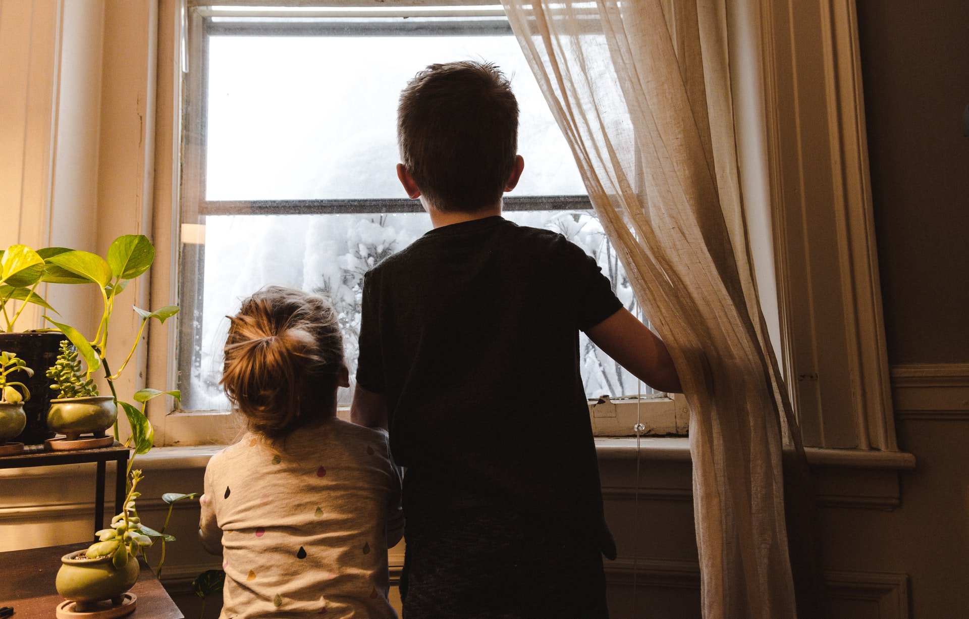 Une petite fille et un jeune garçon regardant par la fenêtre | Source : Unsplash