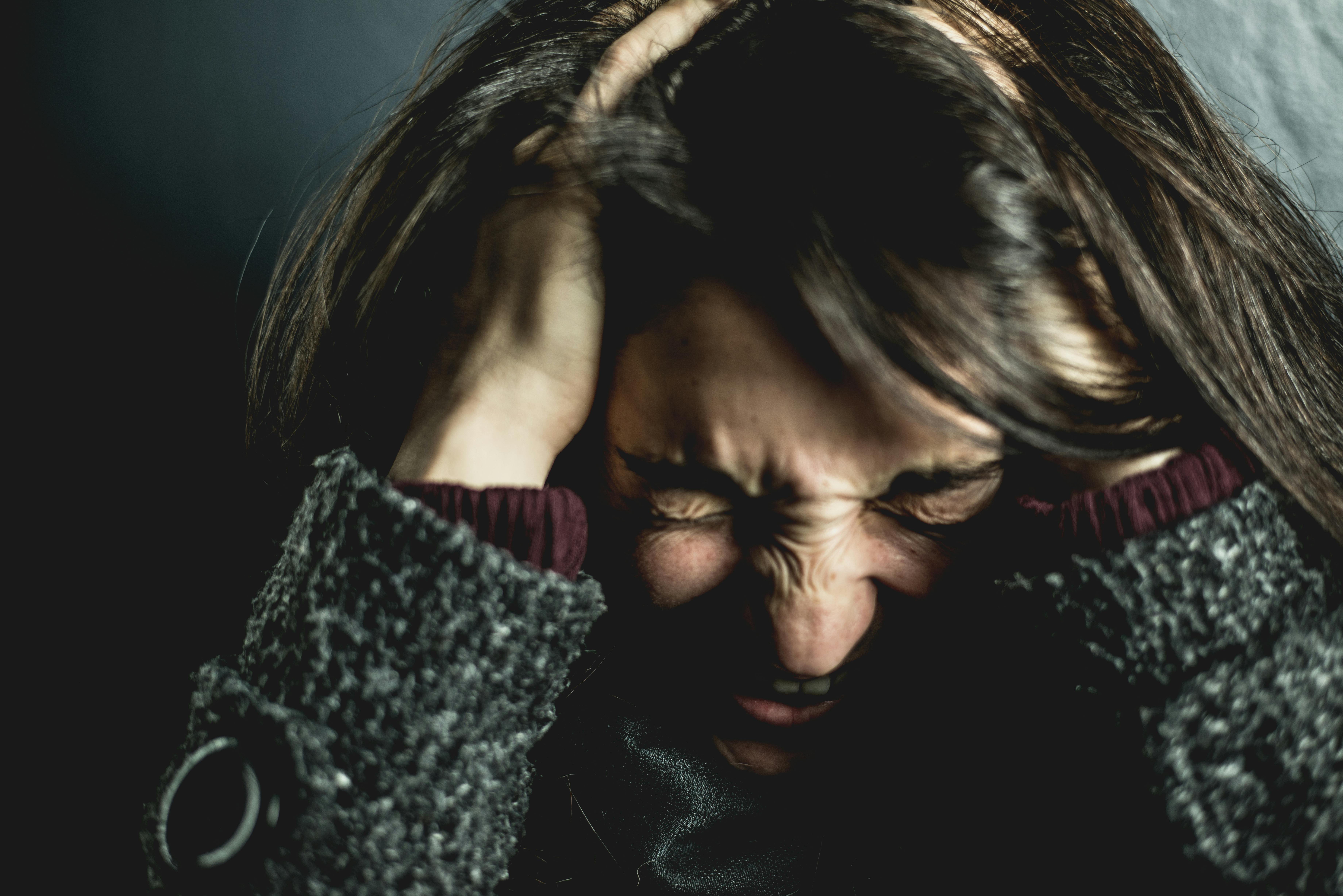 Une femme se couvrant la tête avec ses mains tout en criant de frustration | Source : Pexels