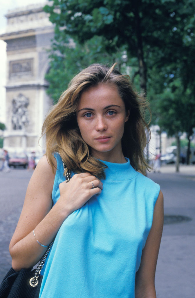 Voici Emmanuelle Béart prise en photo en juillet 1986, en France. Elle est vêtue en bleu et porte un sac noir.