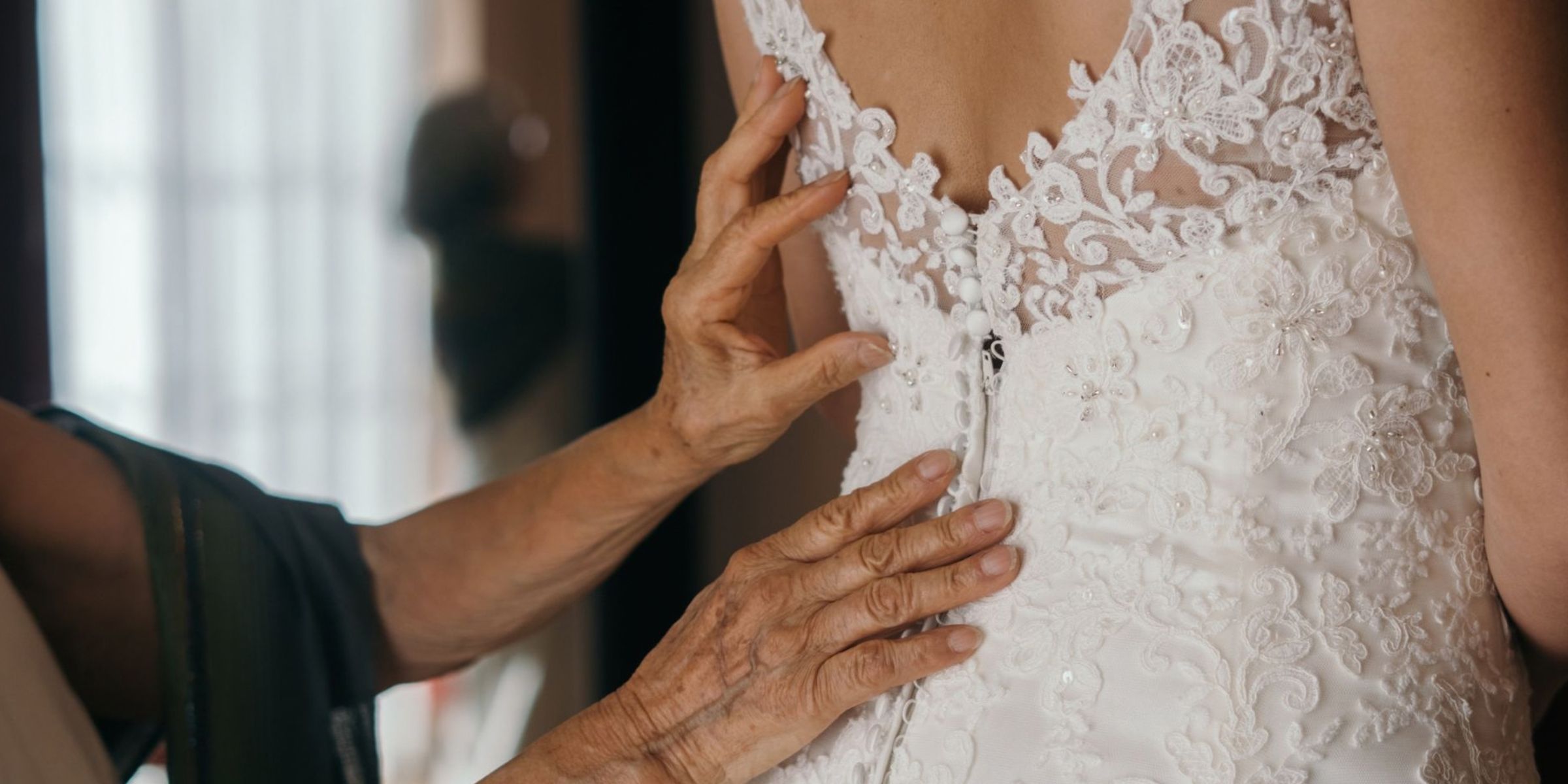 Une mariée qu'on aide à enfiler sa robe de mariée en dentelle | Source : Pexels