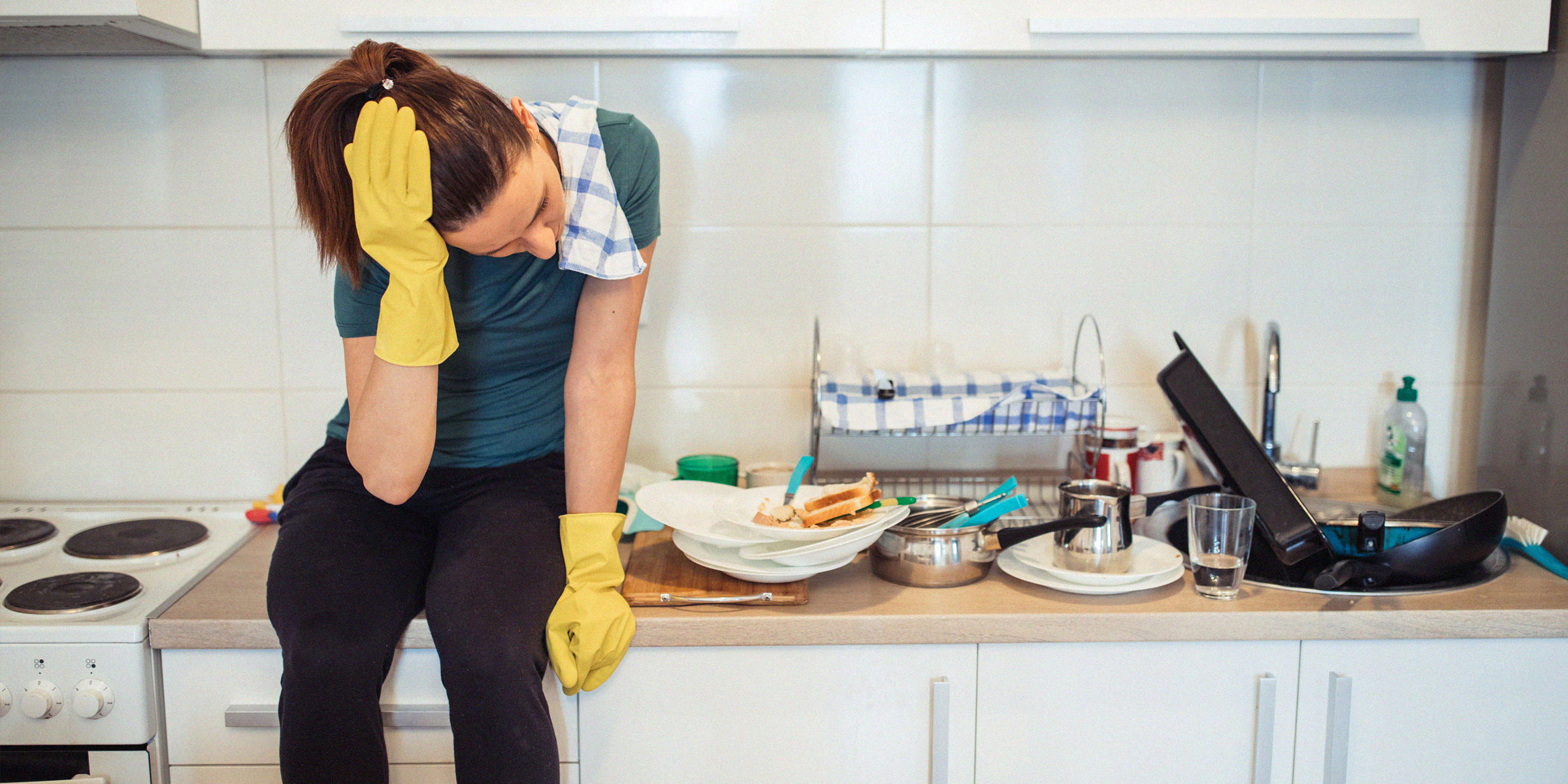 Une maman fatiguée à côté d'un évier de cuisine plein de vaisselle | Source : Getty Images