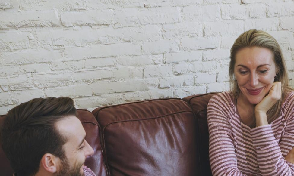 Un homme et une femme ayant une conversation amicale sur un canapé | Source : Midjourney