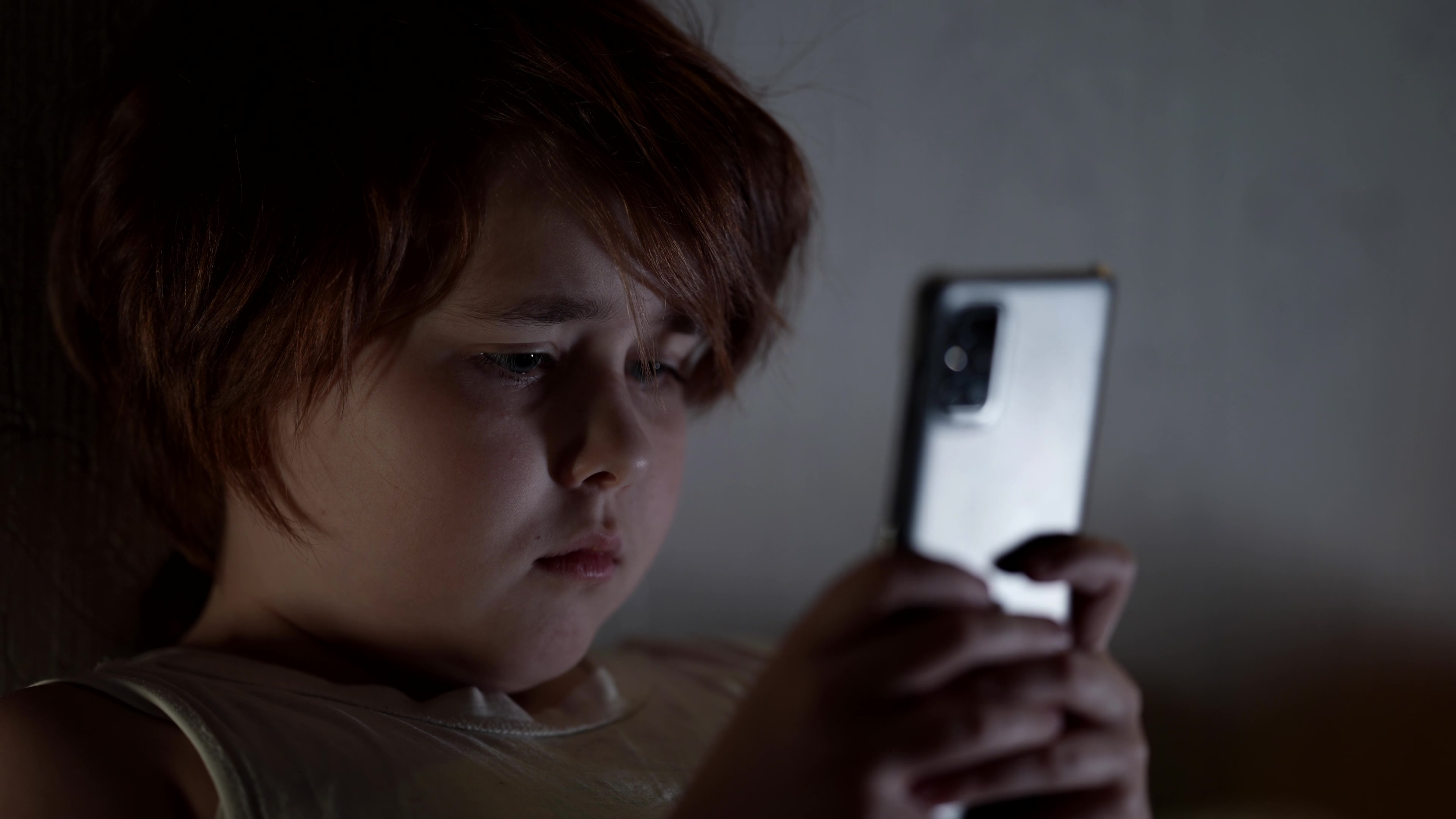 Un enfant qui joue sur son téléphone dans l'obscurité | Source : Shutterstock