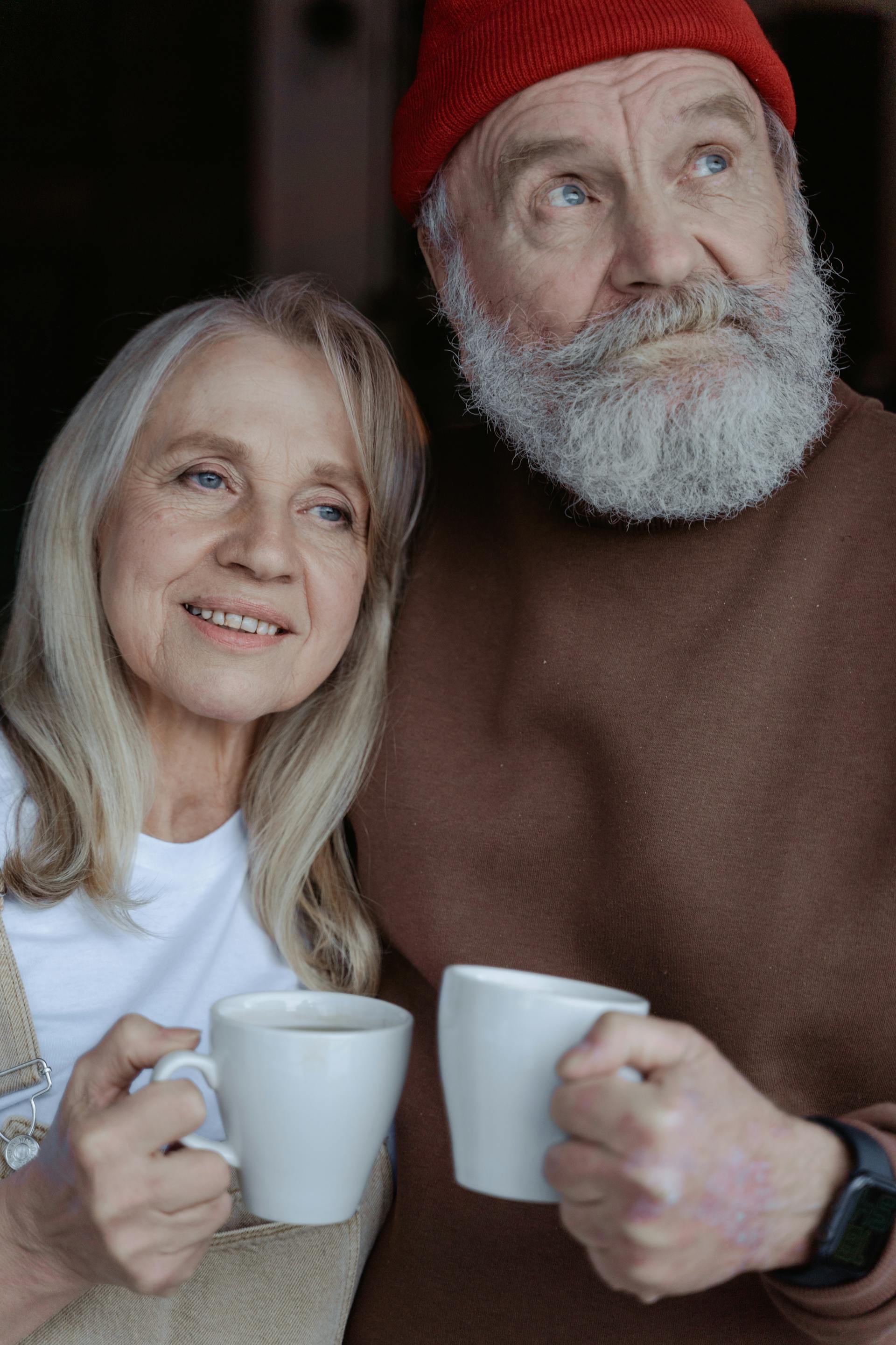 Couple âgé souriant tenant des tasses en céramique | Source : Pexels