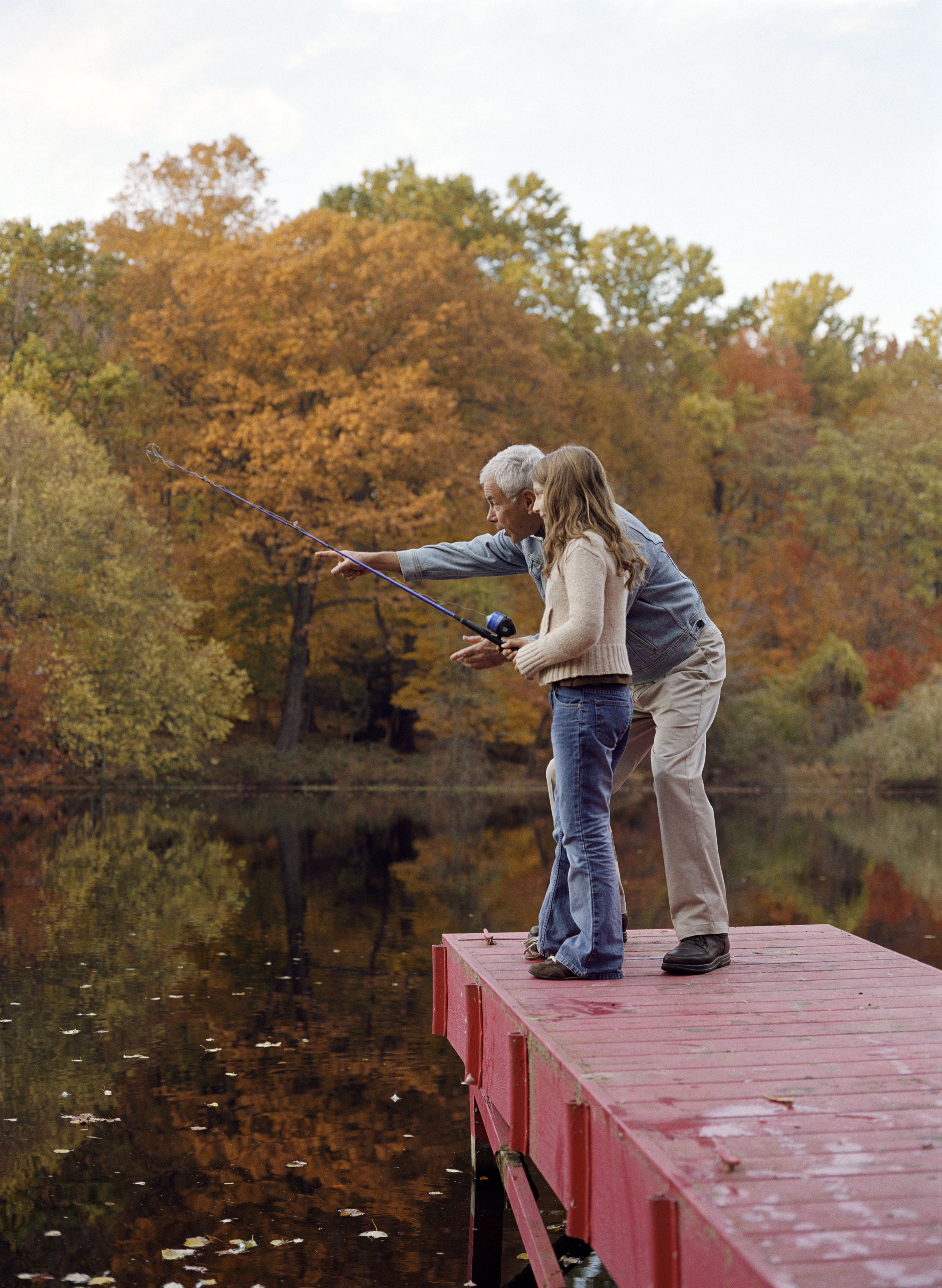 Grand-père et petite-fille (8-10) sur le quai, fille avec canne à pêche | Source : Getty Images