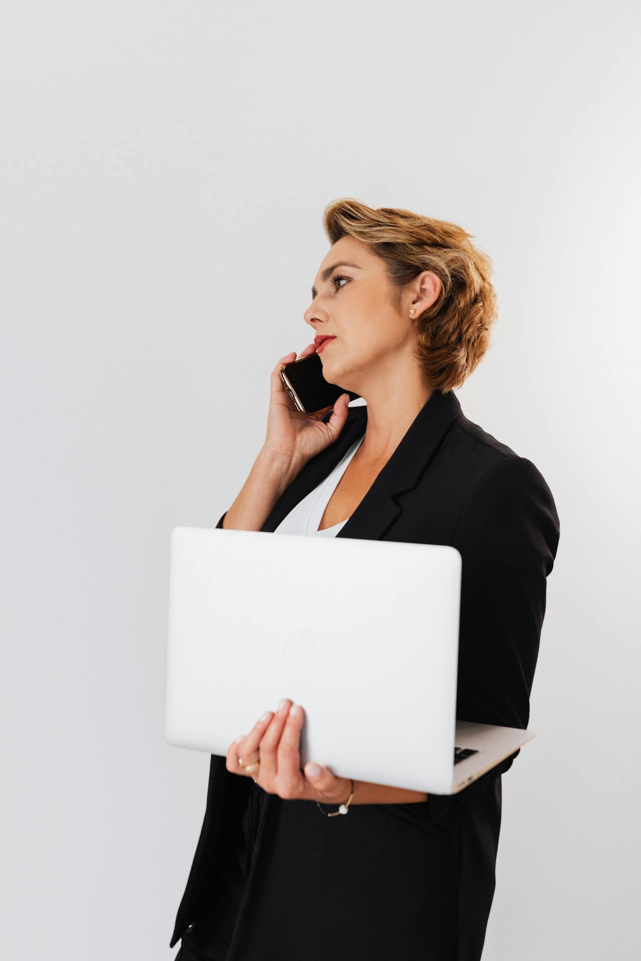 Une femme en train de téléphoner tout en tenant un ordinateur portable | Source : Pexels